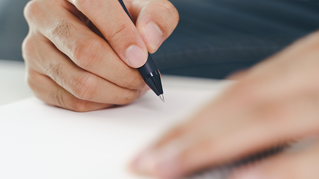 Mann schreibt Notizen in ein Notizbuch als Symbol für Reflexion, Klarheit und mentale Ausrichtung, auch aufgrund der auf dieser Seite angebotenen Downloads.