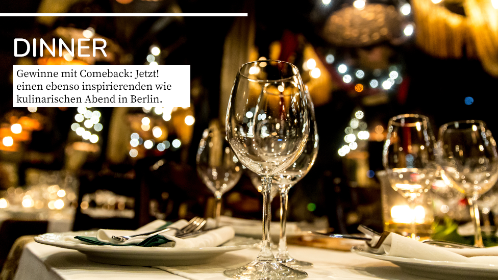 Das Gewinnspiel mit Comeback: Jetzt! – Stimmungsvolles Bild aus der Gastronomie mit einem Tisch im Vordergrund, auf dem Weingläser und Teller mit Servietten und Besteck stehen. Wunderbar warmes Licht im Hintergrund. Headline: Dinner. Text: Gewinne mit Comeback: Jetzt! einen ebenso inspierenden wie kulinarischen Abend in Berlin.